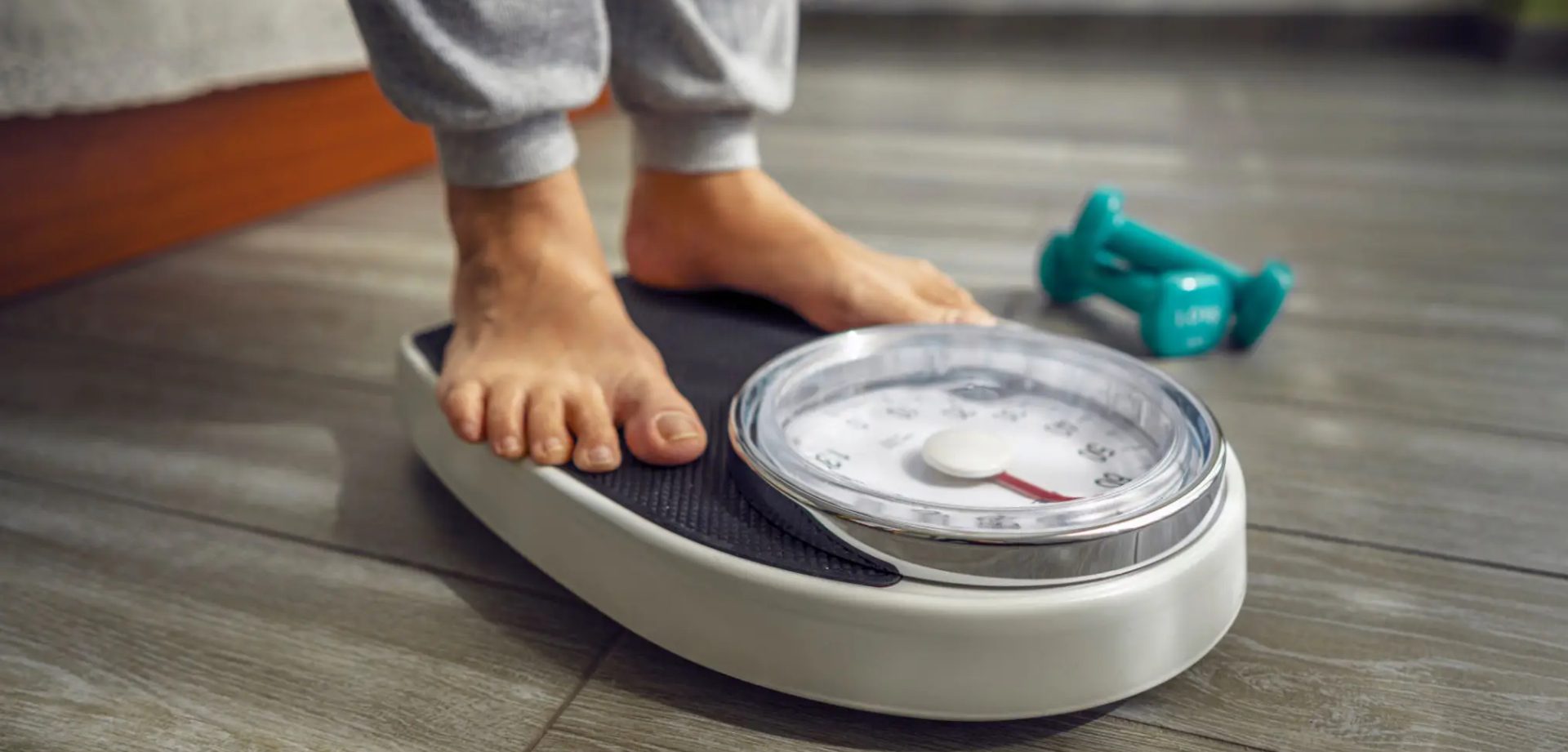 Person standing barefoot on an analog weighing scale indoors.