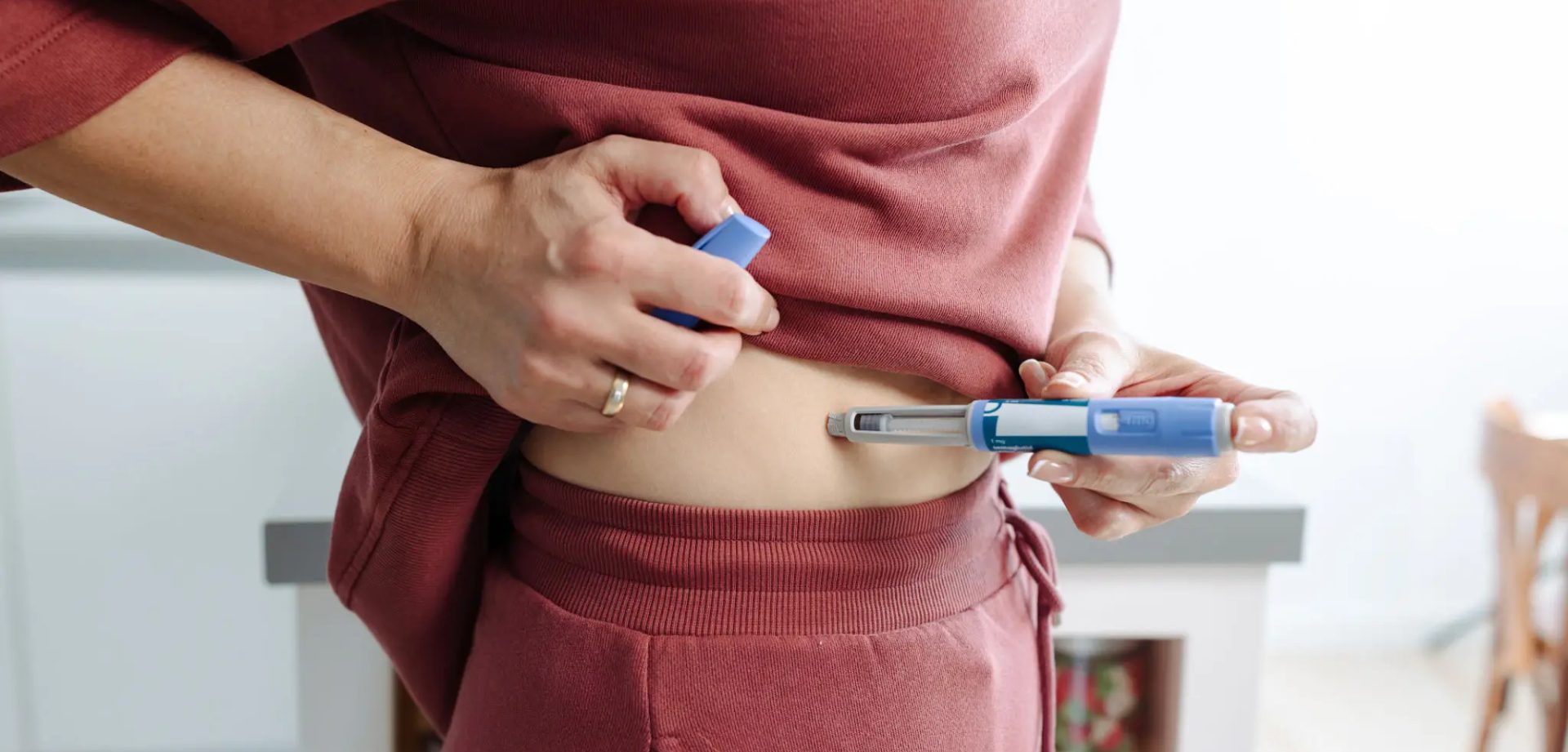 Person injecting insulin into their abdomen using a syringe.