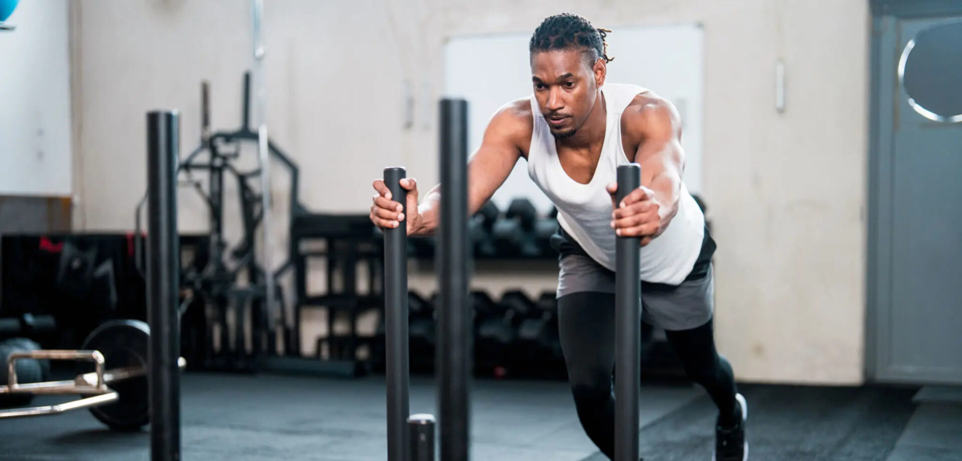 Athlete pushing sled in gym, focused on strength training.