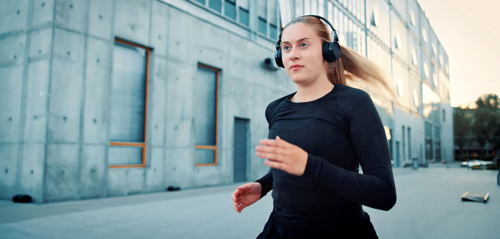 Woman jogging outdoors wearing headphones.