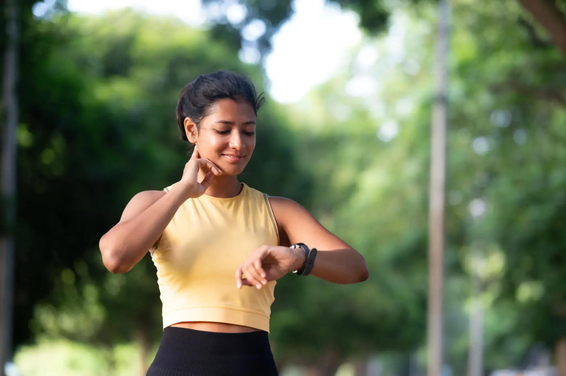 Woman checking her smartwatch outdoors in workout attire.
