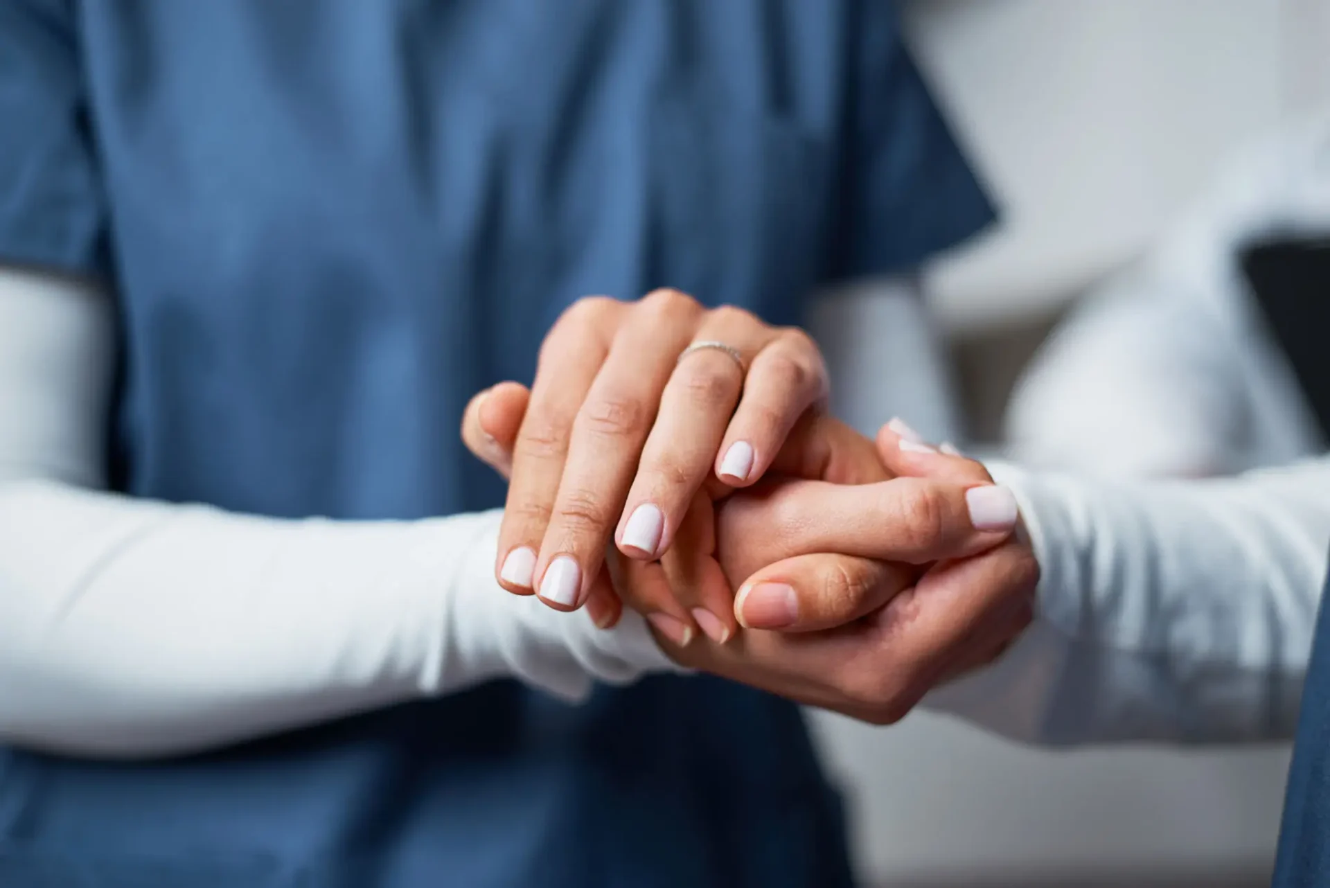 A healthcare worker holding a patient's hand for comfort.