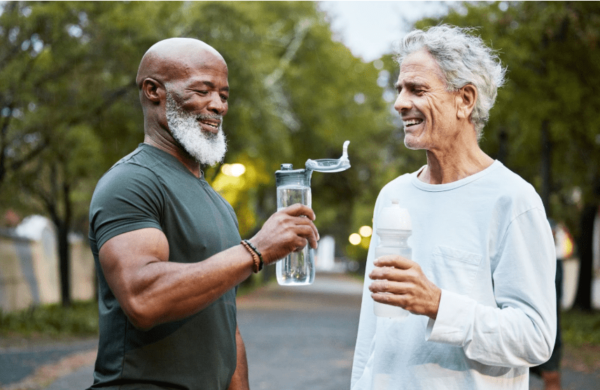 Two men enjoying drinks and sharing a laugh outdoors.