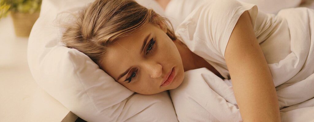 Woman awake in bed after unrefreshing sleep while a sleep study tracks overnight breathing