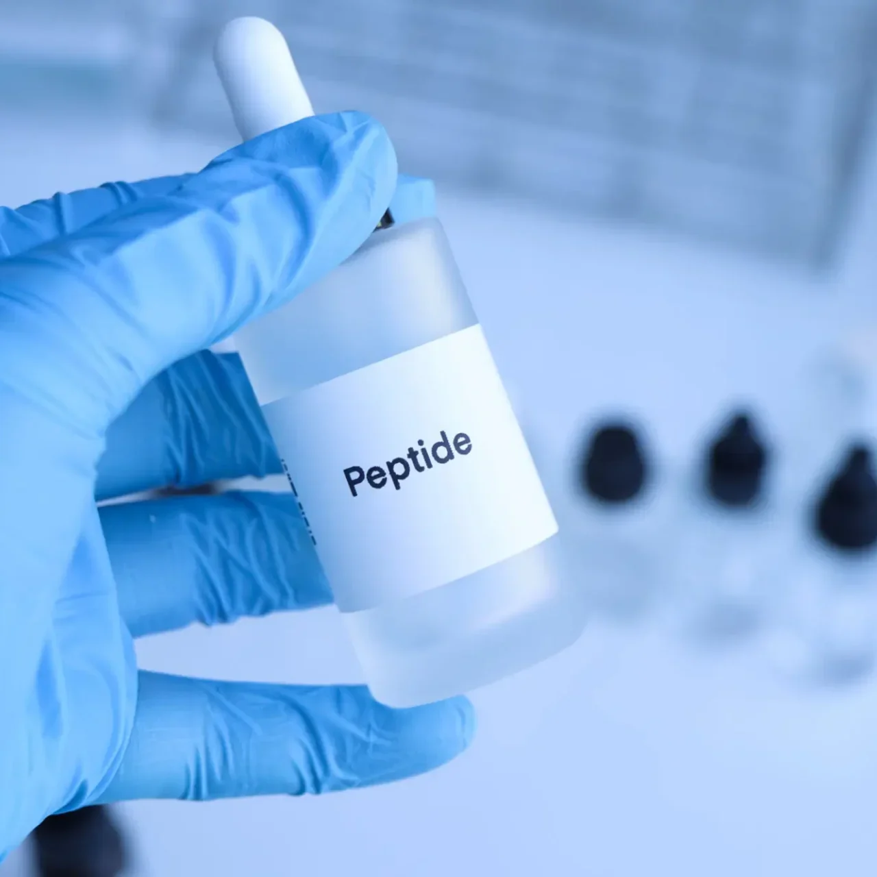 Hand holding a dropper bottle labeled 'Peptide' in a lab setting.