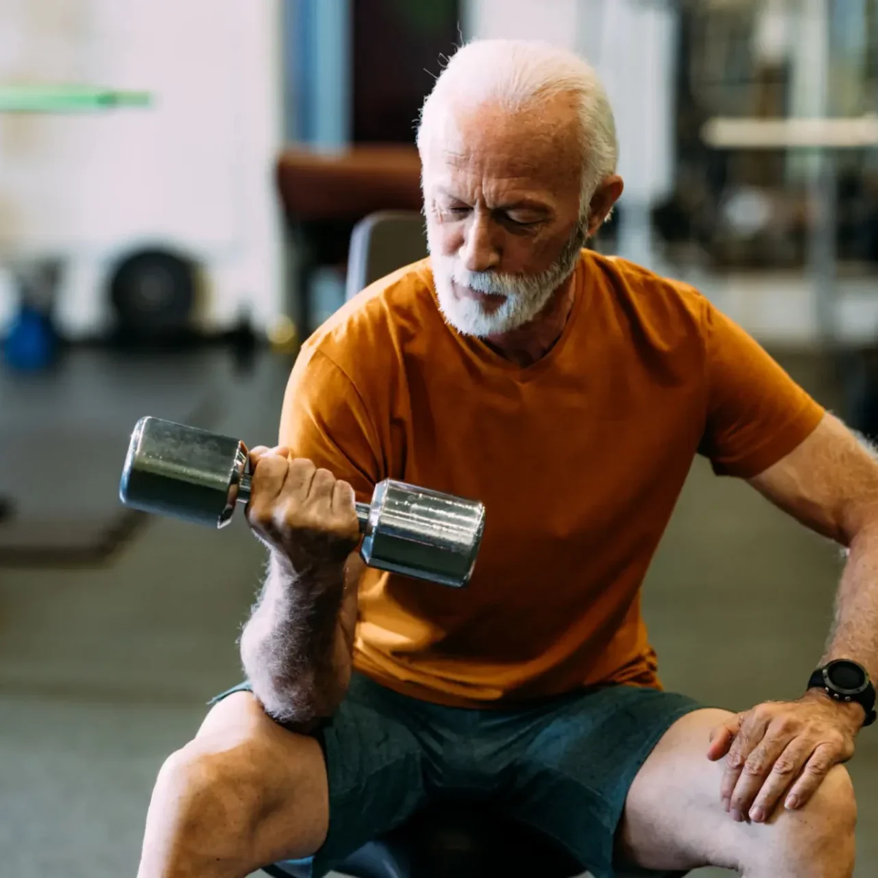 Elderly man lifting a dumbbell while exercising indoors.