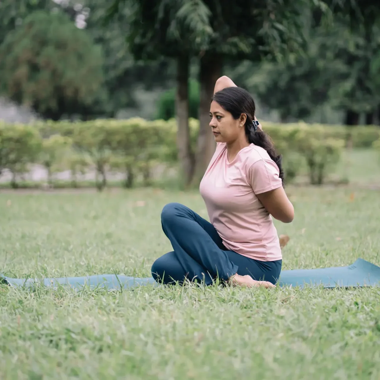 Woman practicing yoga outdoors in a seated twist pose.